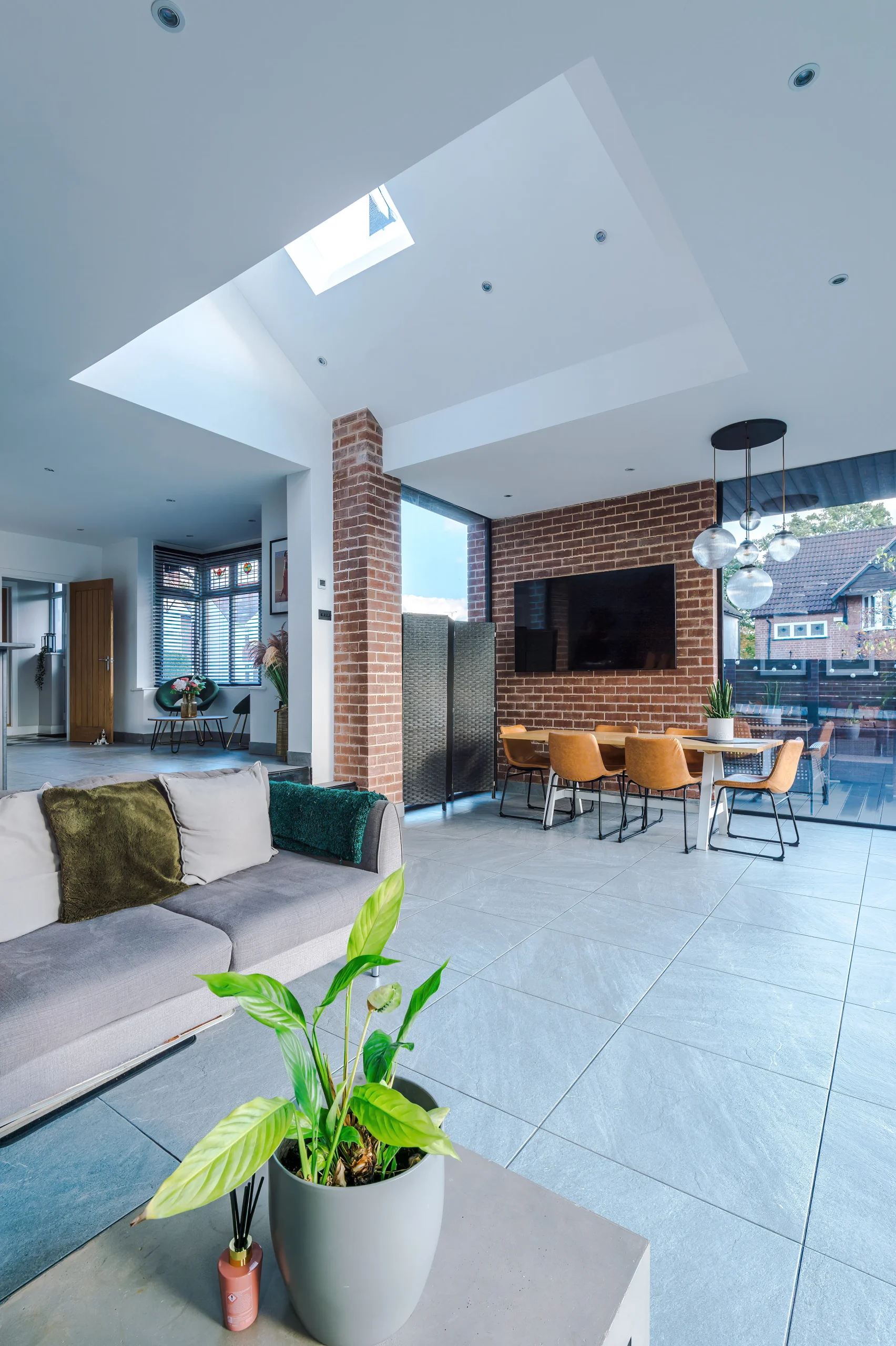 View of open plan space linking lounge and dining at the lower level, with reading nook and kitchen at the higher level, and vaulted ceiling above.