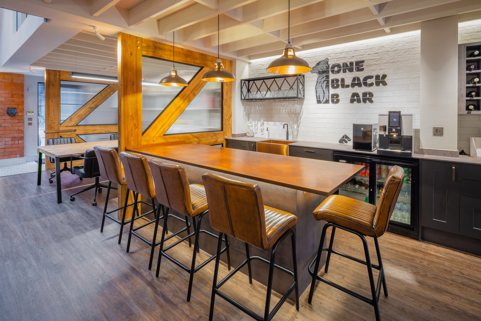 The bar is located within open plan space at ground floor level, separated from the workstation by screens made from the old roof truss.