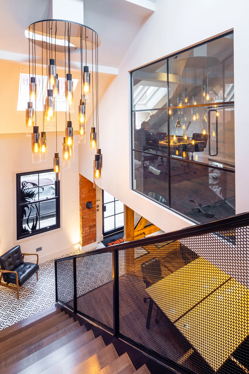 View across newly formed double height space with feature lighting over stair and directors’ office in the background.