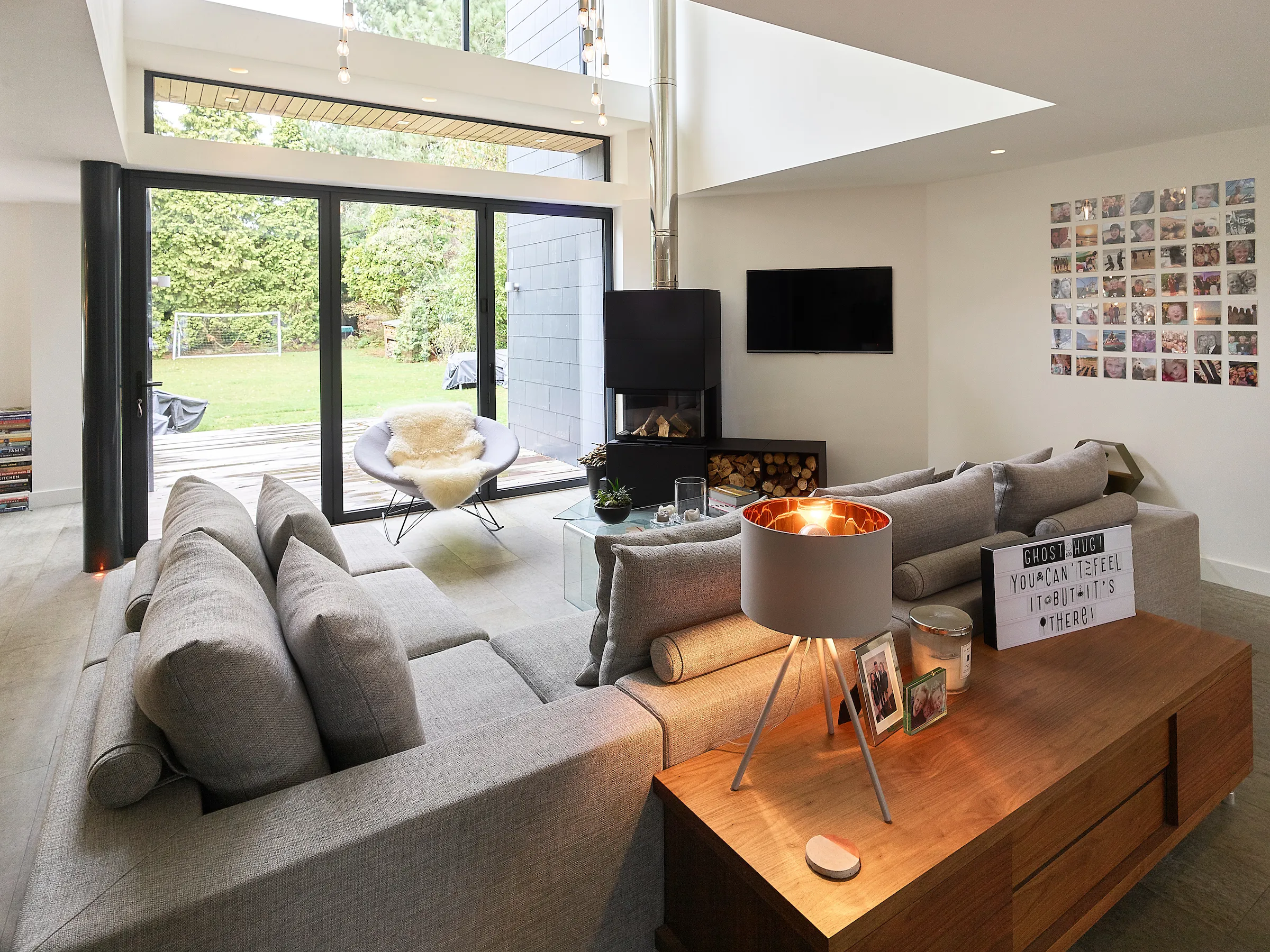 Open plan space focusing on lounge with log burner and double height atrium above
