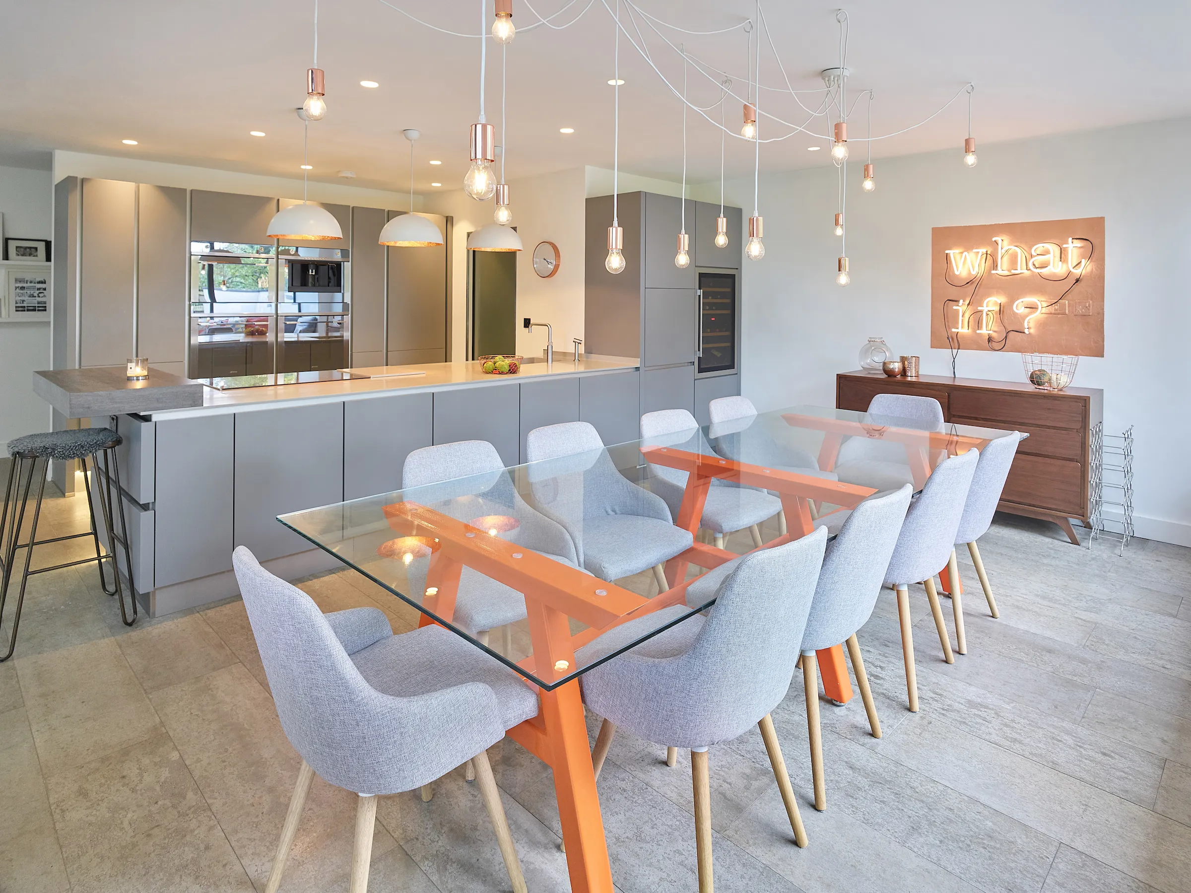 Grey kitchen linked with dining with glass table