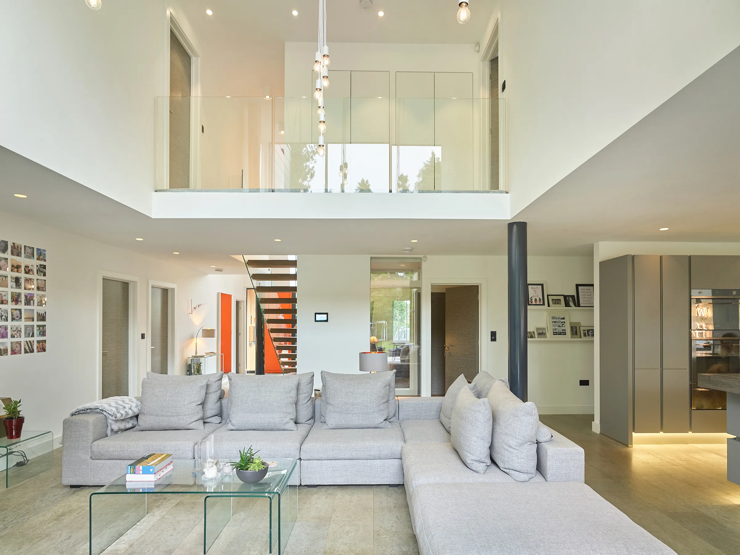 Open plan space focusing on lounge linking with entrance hall and kitchen, with double height atrium above and connecting bridge