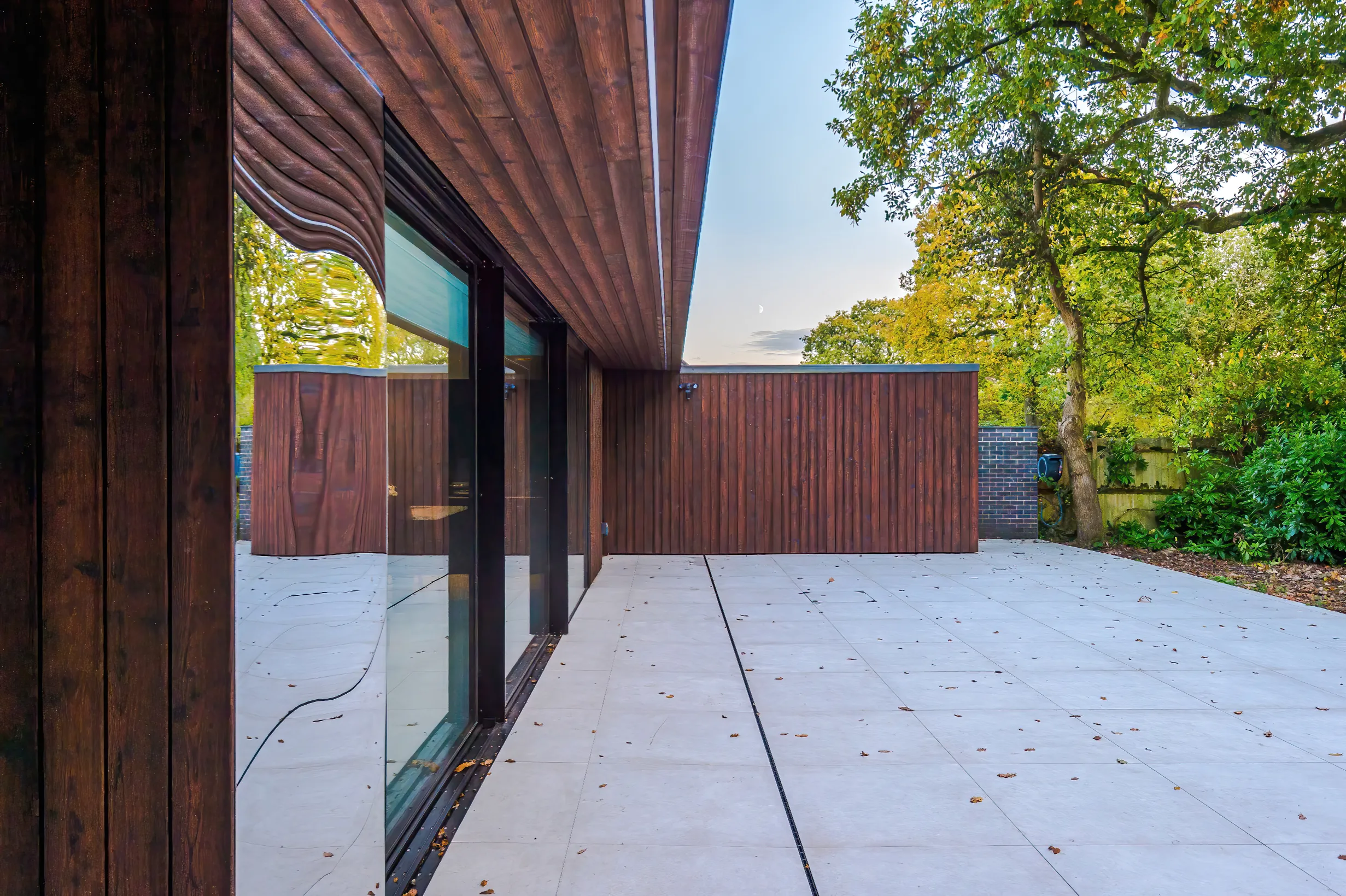 View of the rear, with mirror cladding in the foreground, the toilet and storage block projecting in the background, and timber clad soffit hovering above.