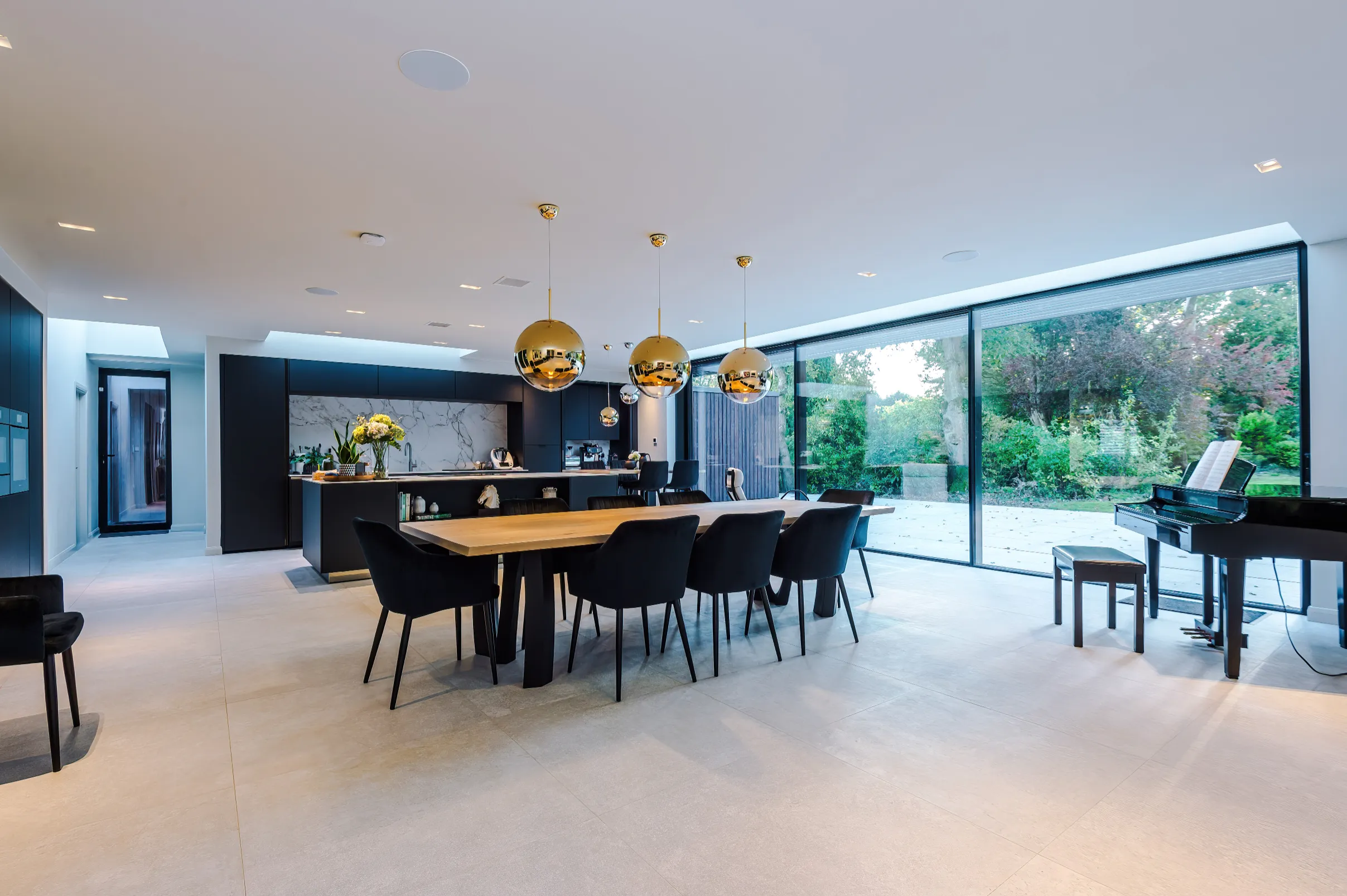 Open plan space linking kitchen, dining and music zones, with views to the garden through triple glazed sliding doors.