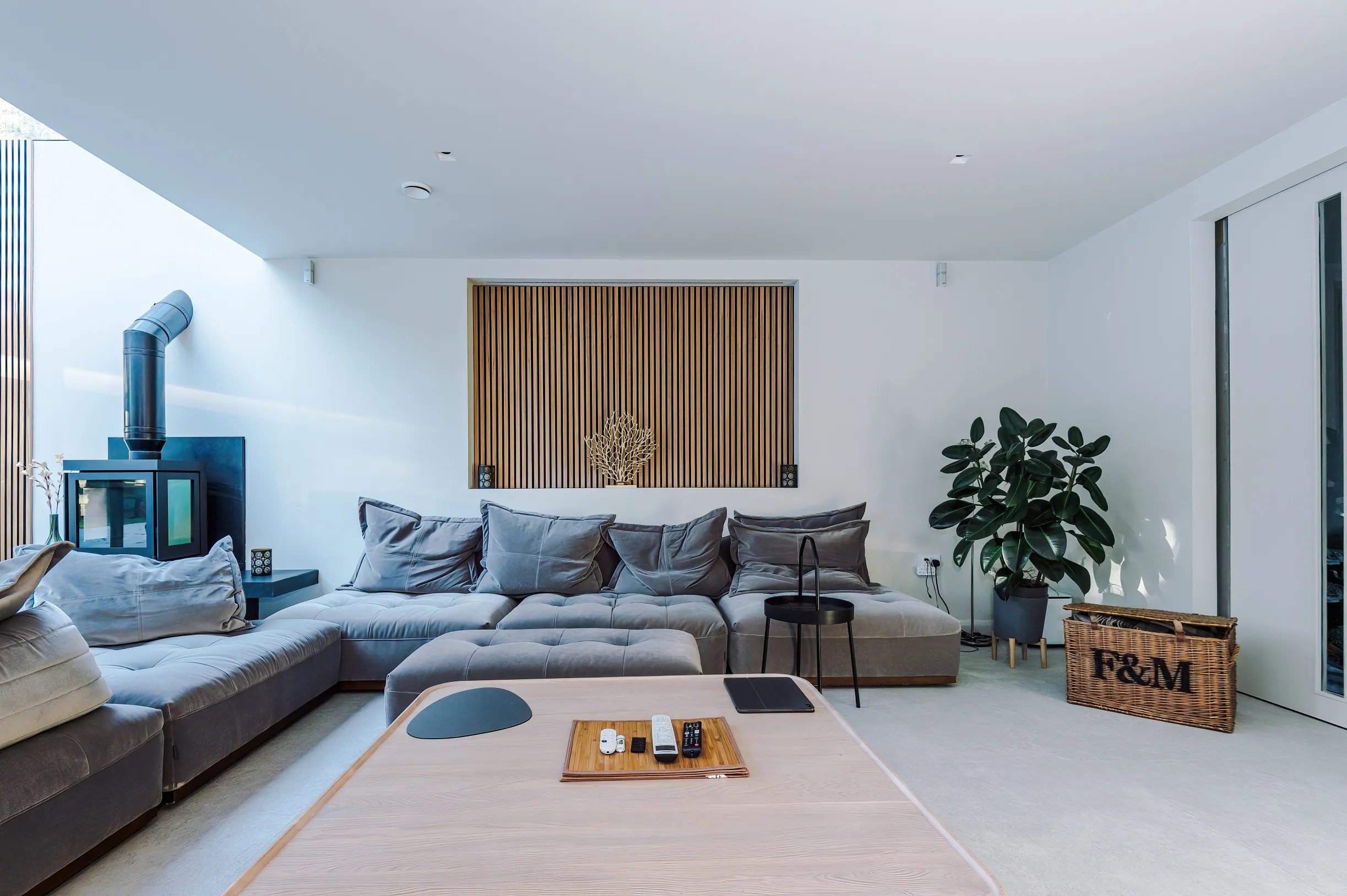 View of lounge with recessed feature timber panelling and log burner to the side.