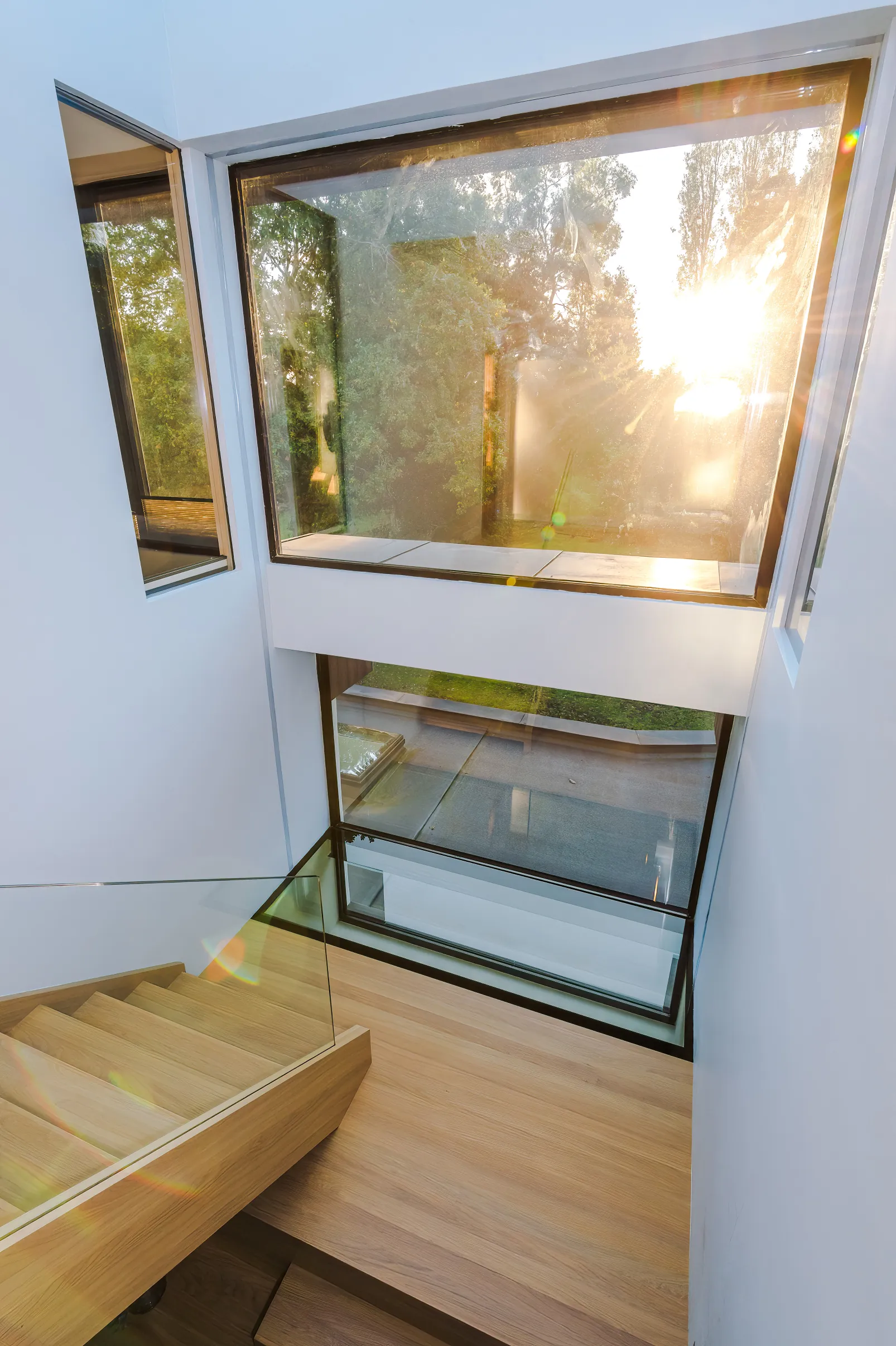 Loft stairwell featuring timber stairs, partially glazed landing floor, and glazing and views to the garden.