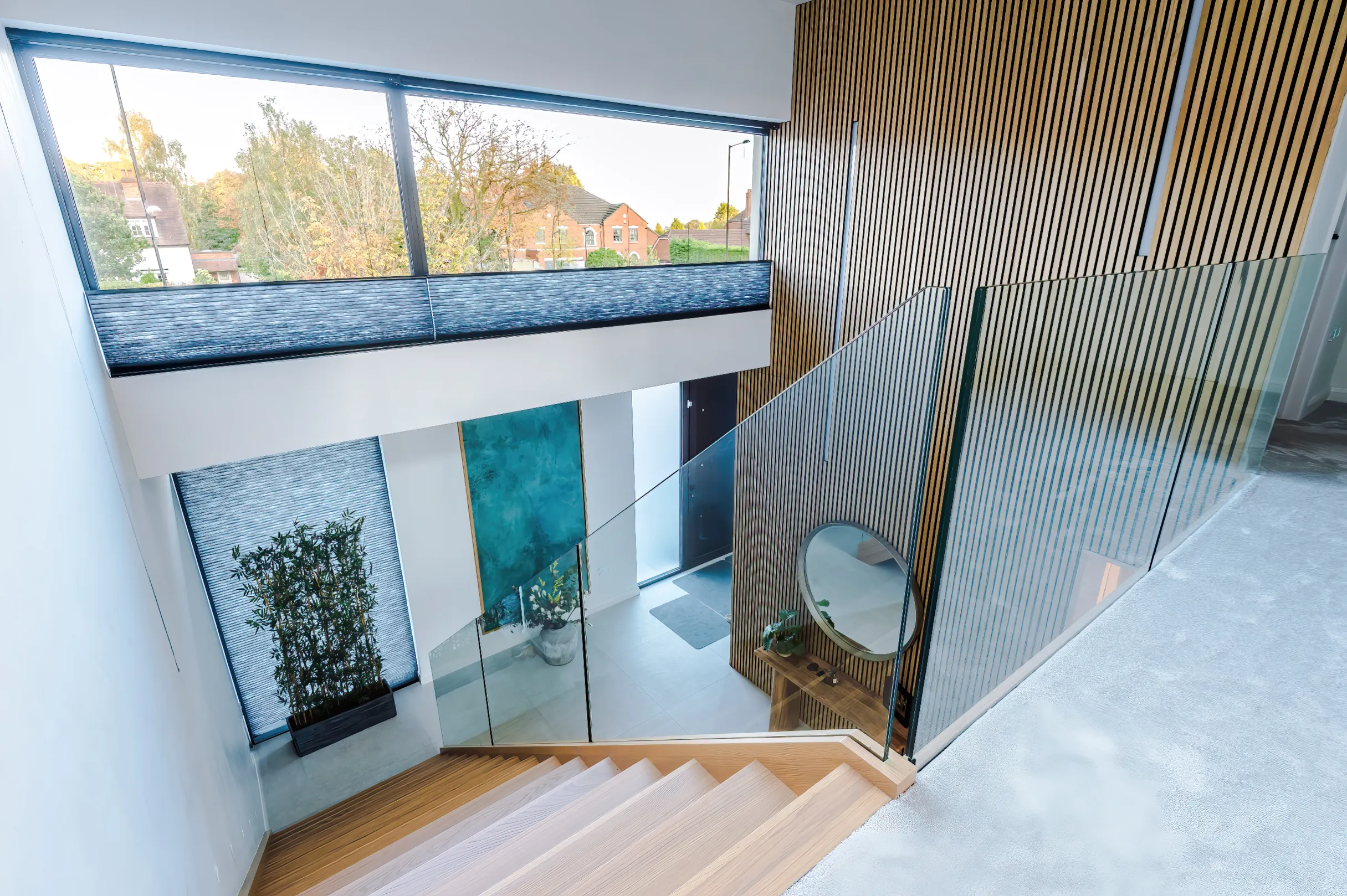 View looking across double height entrance hall, featuring timber stairs and wall cladding.