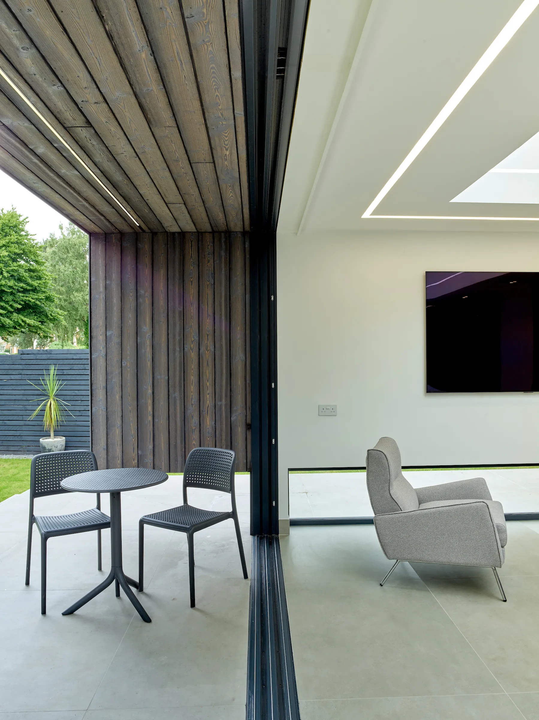 View at the seam between inside and outside spaces, with a floating wall and canopy in the backdrop