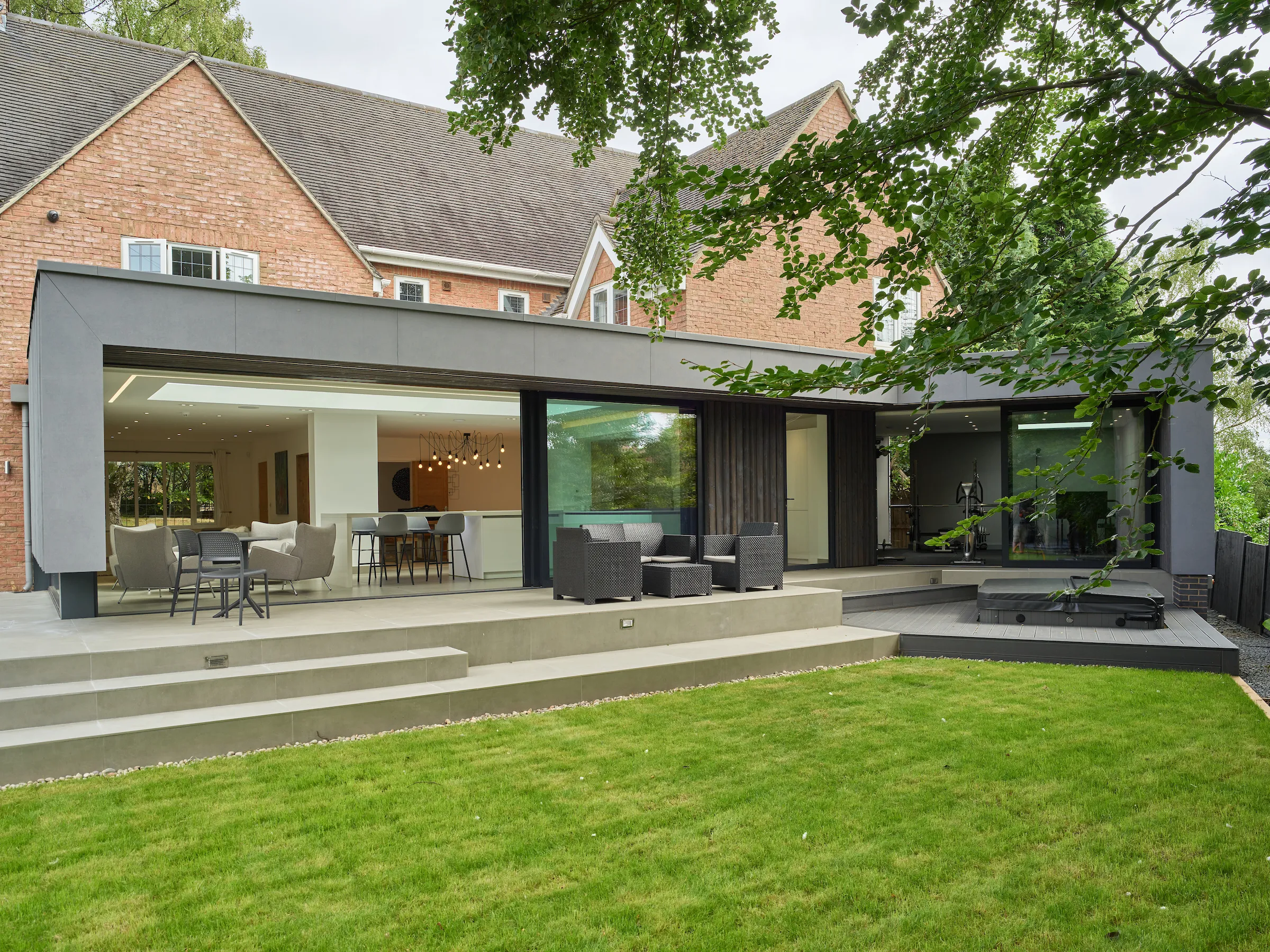 View of the contemporary extension sweeping across the rear face of the traditional red brick house