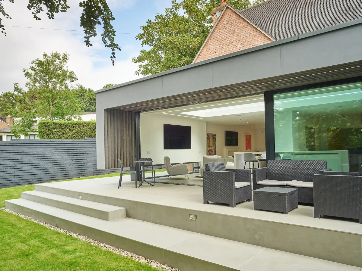 View of the raised terrace in the foreground, with the deep canopy providing sheltered space at the transition from inside to outside.
