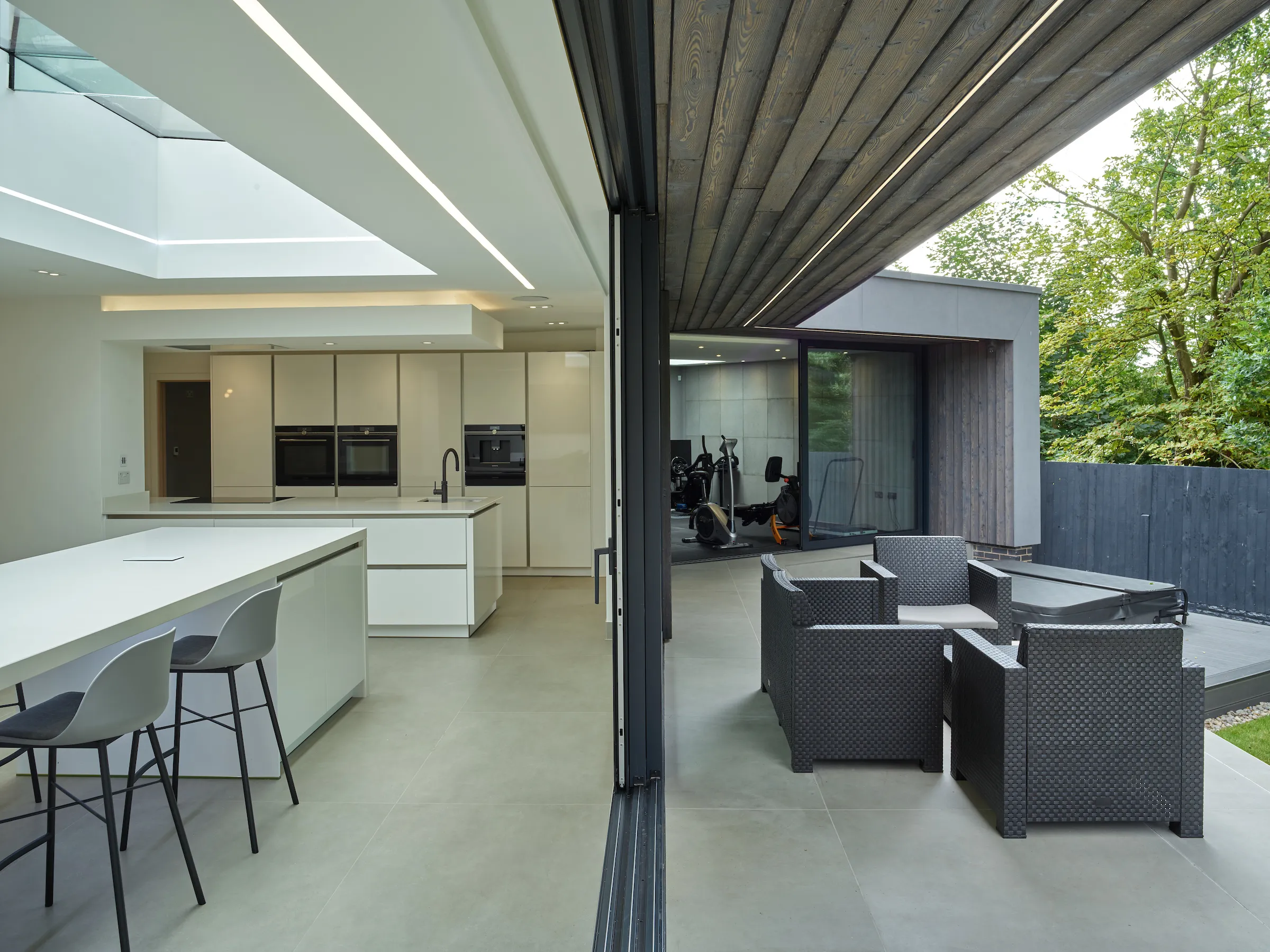 View at the seam between inside and outside spaces, featuring 2 kitchen islands, a gym and a hot tub.