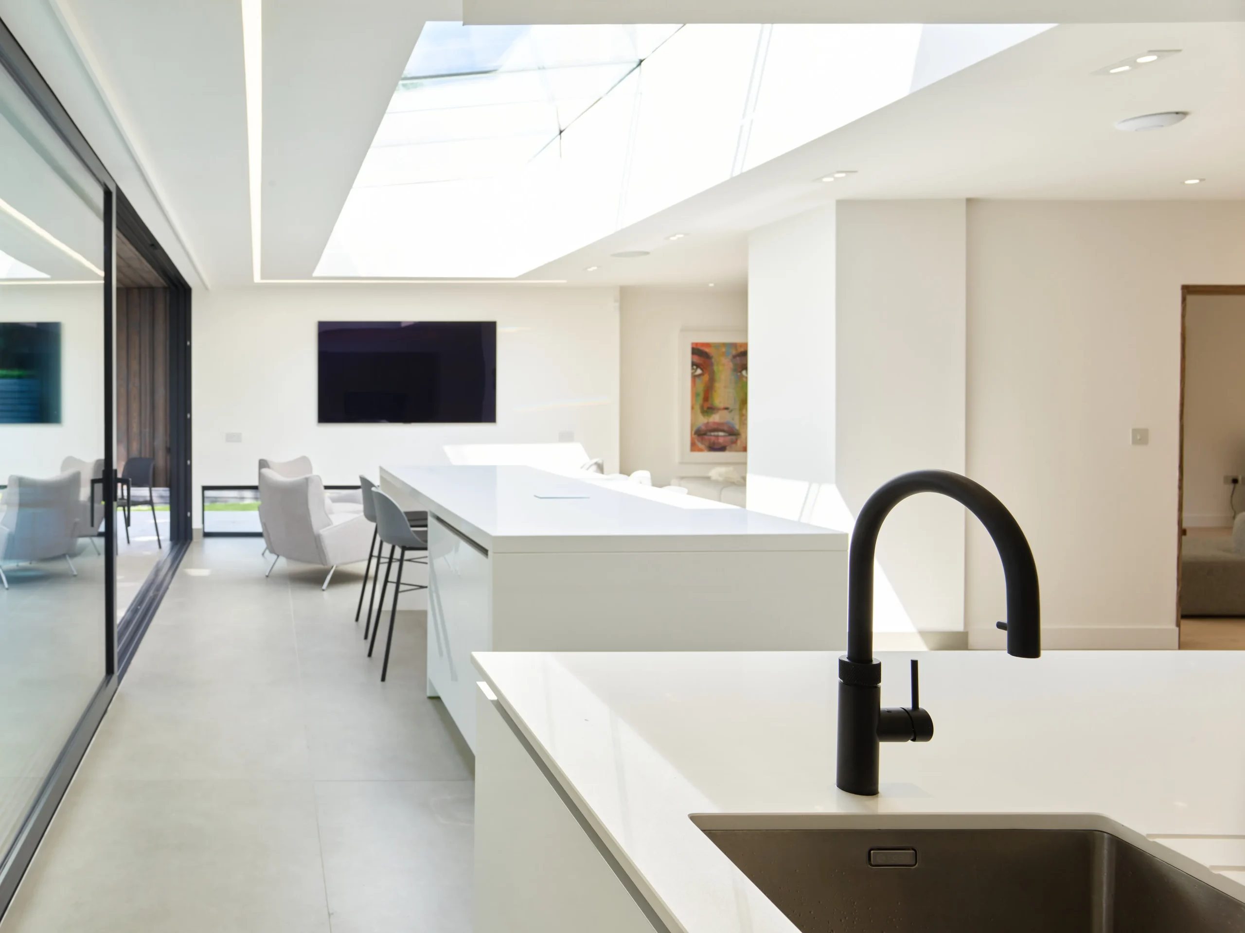 View of the open plan kitchen featuring a working kitchen island in the foreground and a social island at the rear, with a large rooflight above flooding the space with light