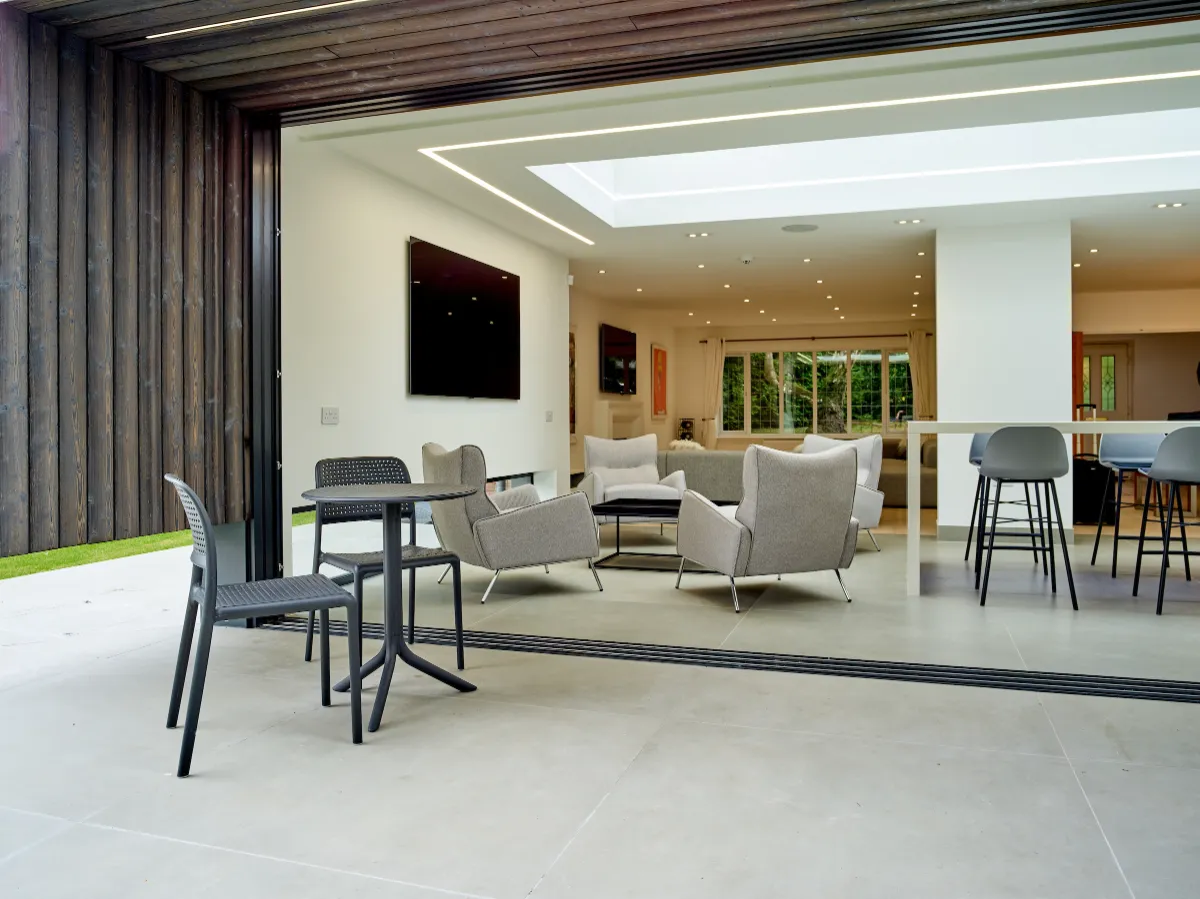 View across the raised terrace and open sliding doors, into the open-plan space linking kitchen and lounge.