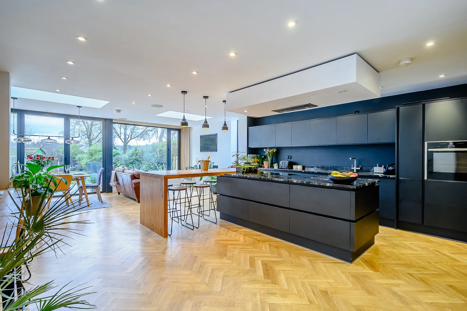 Black kitchen linked to lounge and dining