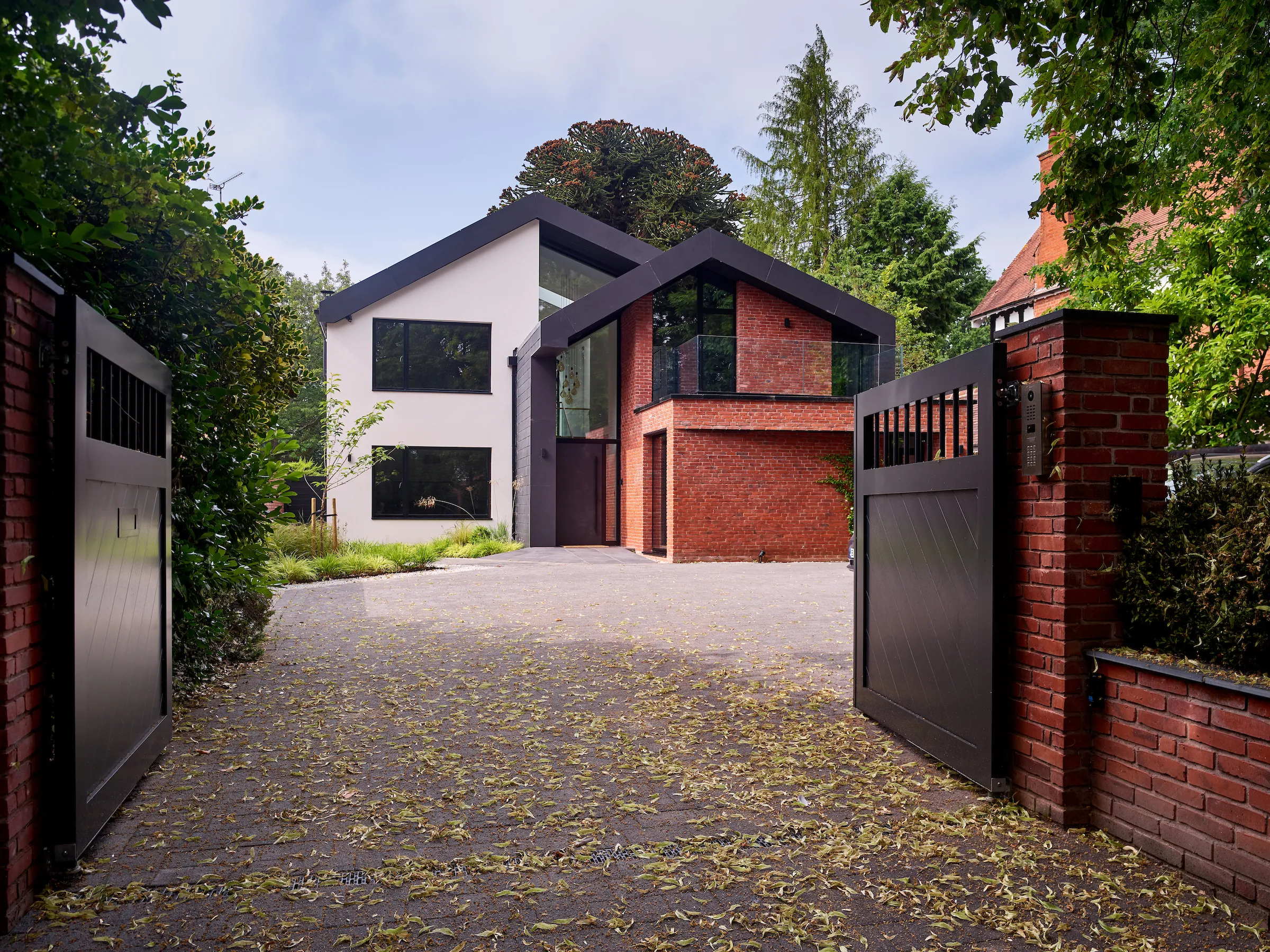 Front of dwelling double height glazed entrance feature with folding slate roof and a combination of red brick and render finishes
