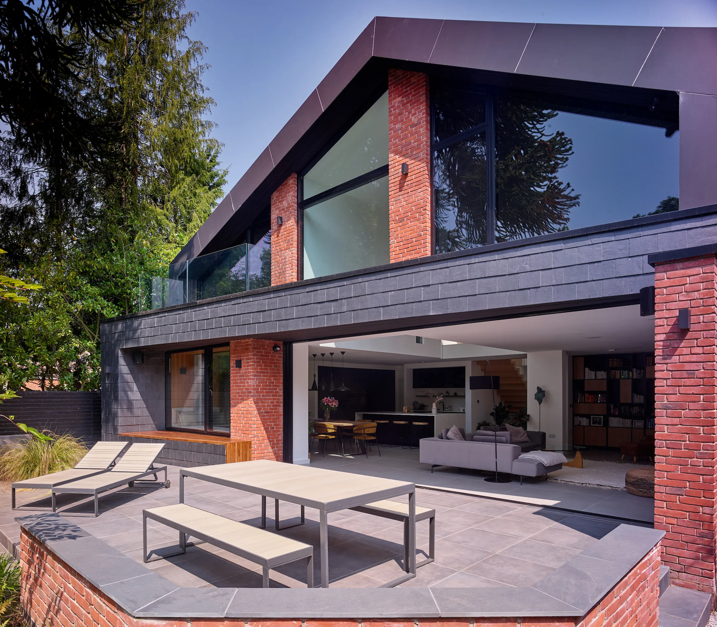 Rear elevation showing folding planes clad in slate and Equitone. Large sliding doors