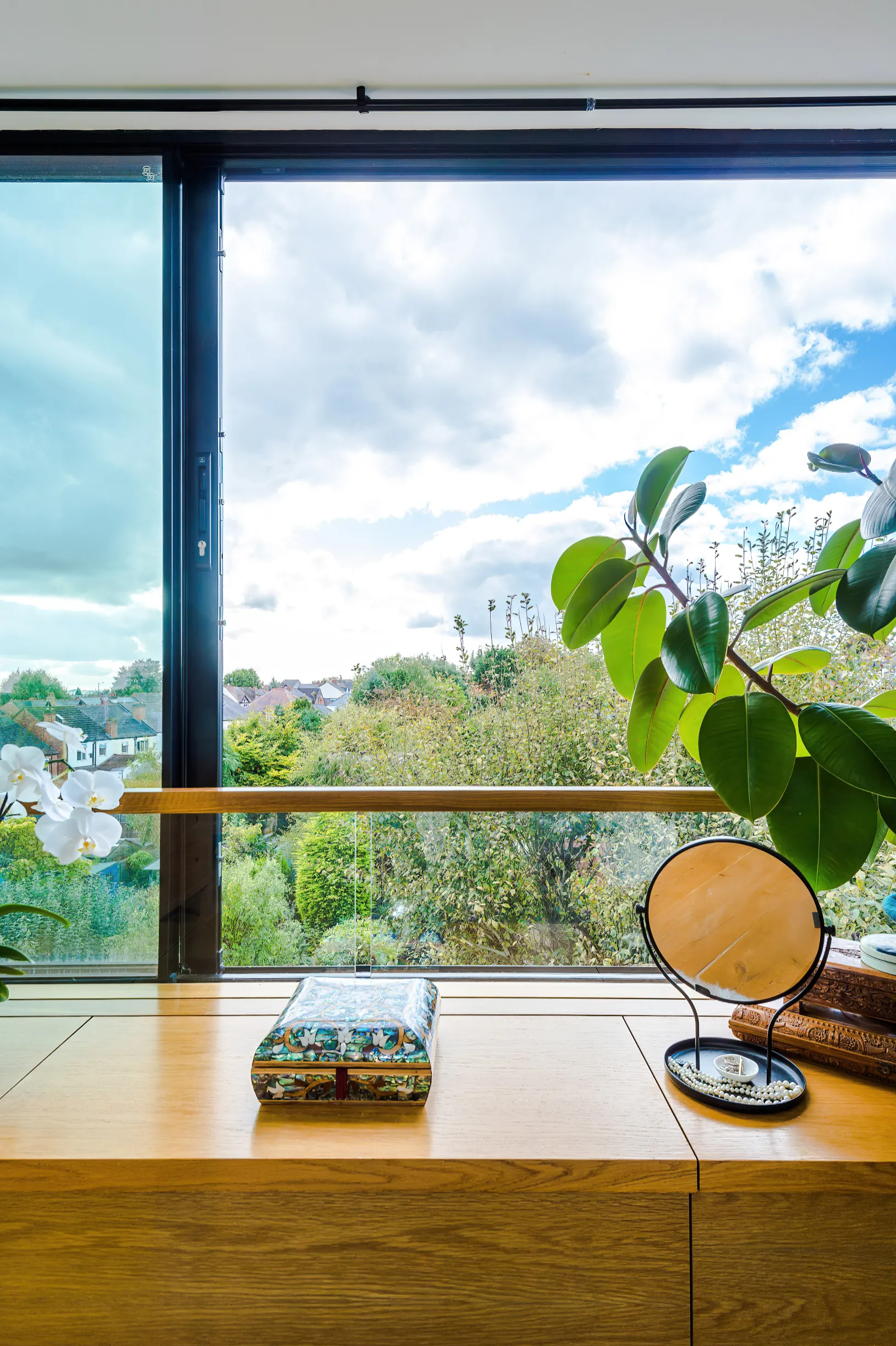 An oak window seat with hinged top sections provides elegant storage. An integrated glass balustrade with an oak handrail provides safety when the sliding door is open.