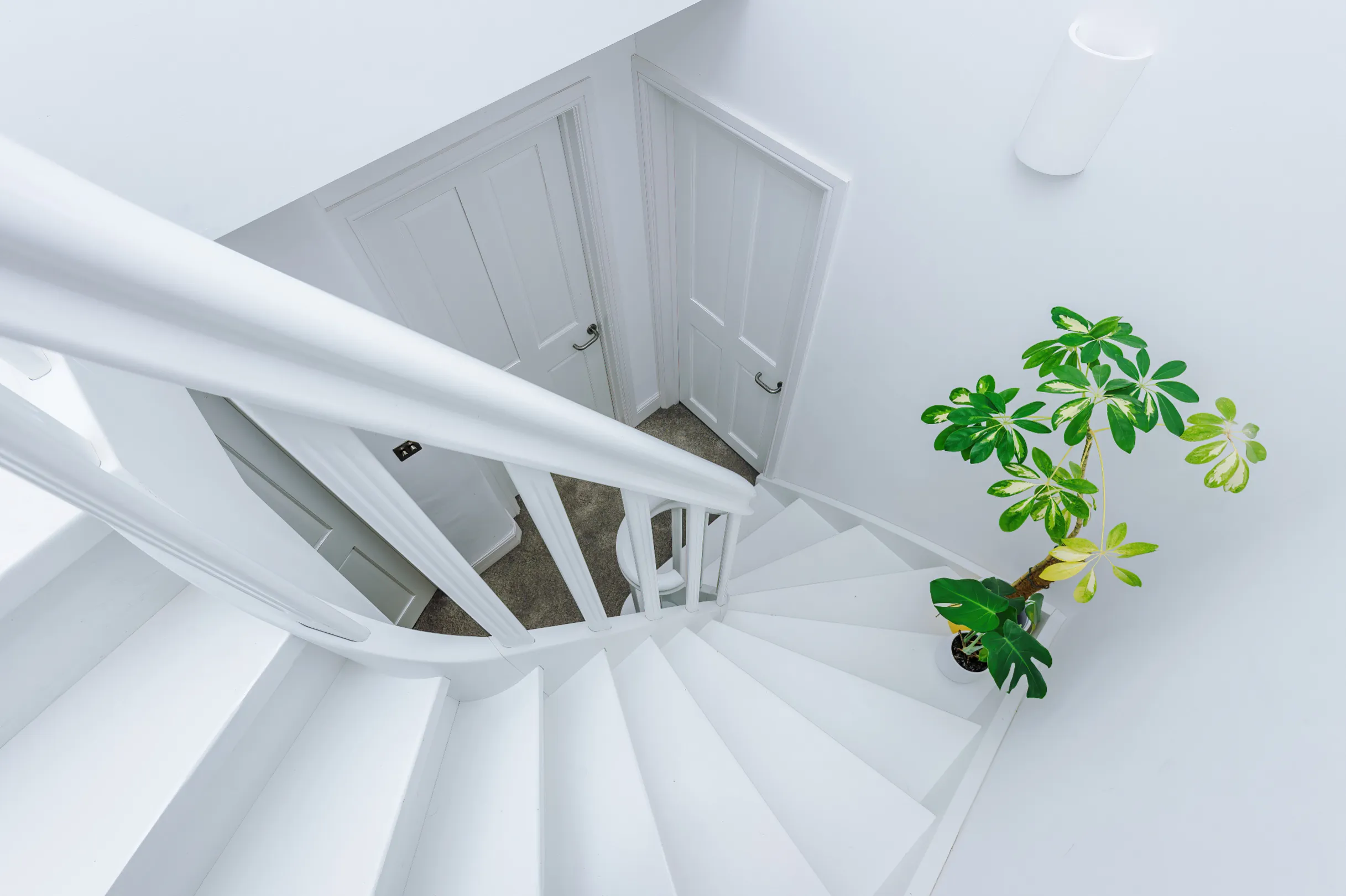 A white winder stair in a stairwell flooded with natural light, provides elegant access to the converted loft.
