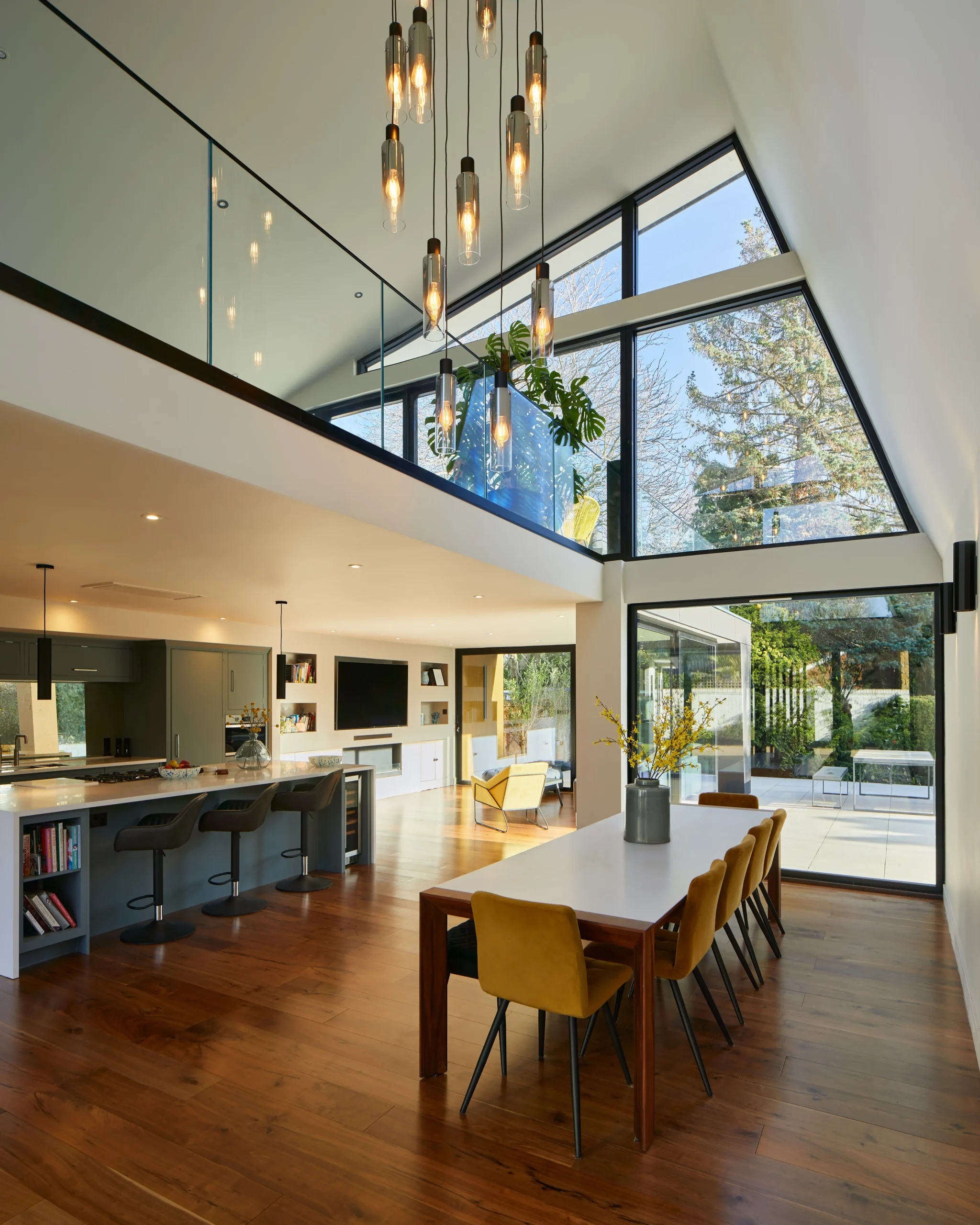 Double-height open-plan kitchen, dining and living space with roof glazing bringing daylight deep into the interior