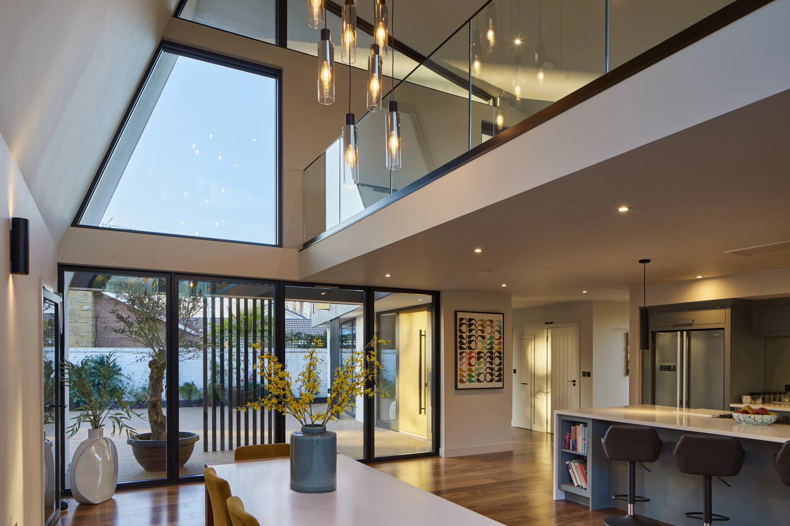 Interior view of dining area with mezzanine balustrade, roof glazing, and screened views to the front courtyard