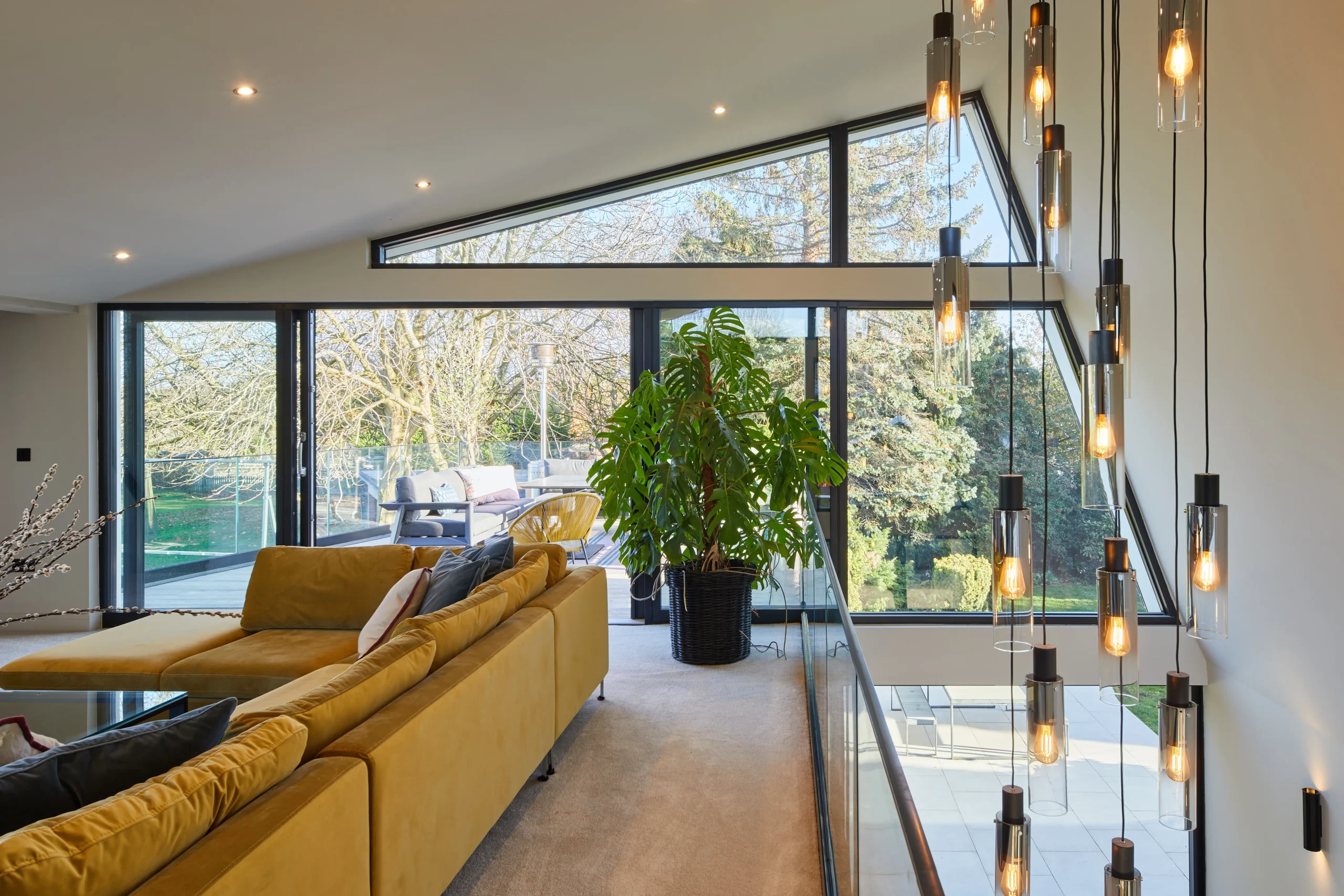 Upper-level living space with angled roof glazing and floor-to-ceiling windows opening onto a first-floor terrace