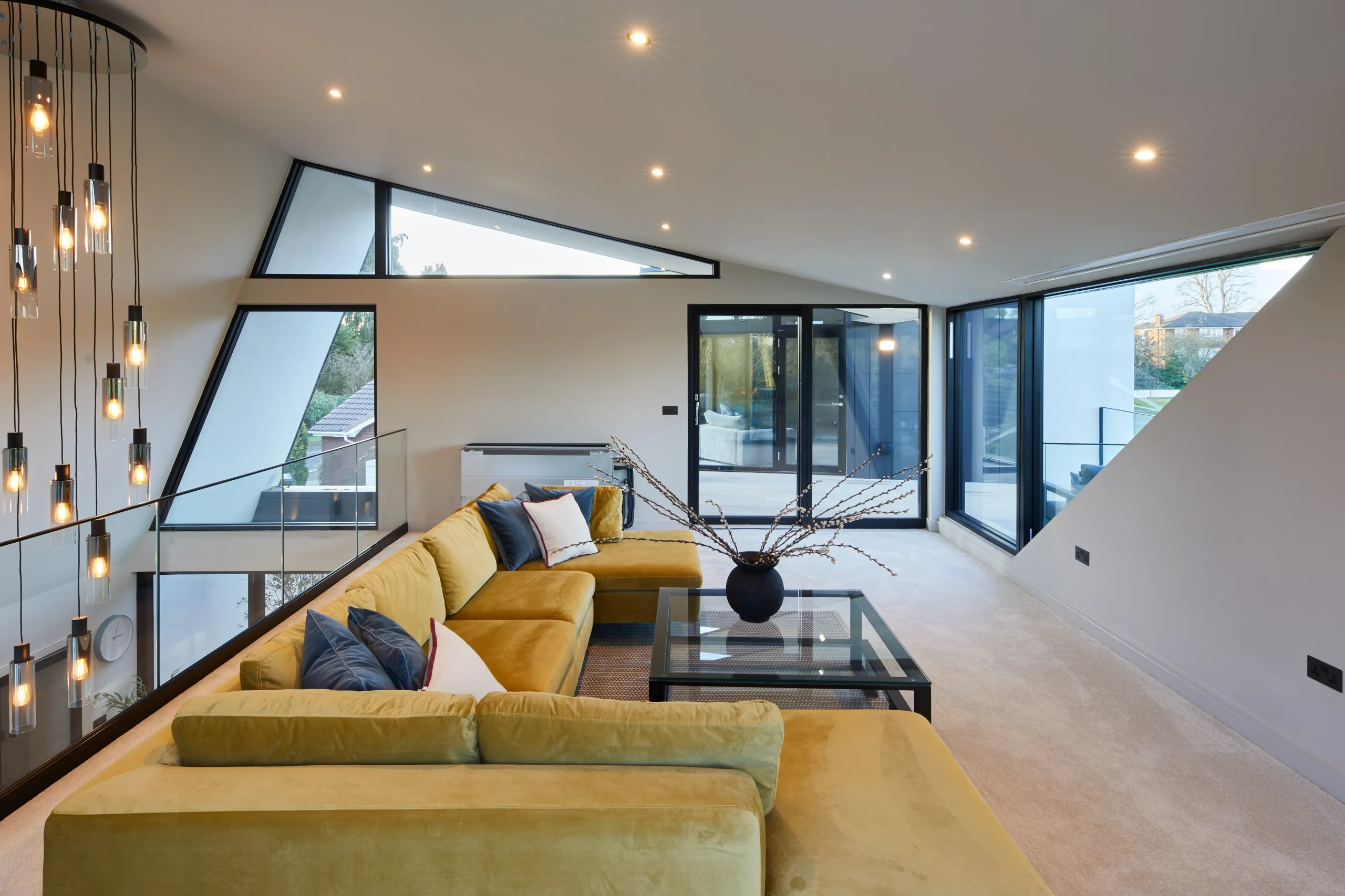 First-floor living room defined by sloping ceiling, angled windows, and full-height glazing opening to an elevated terrace