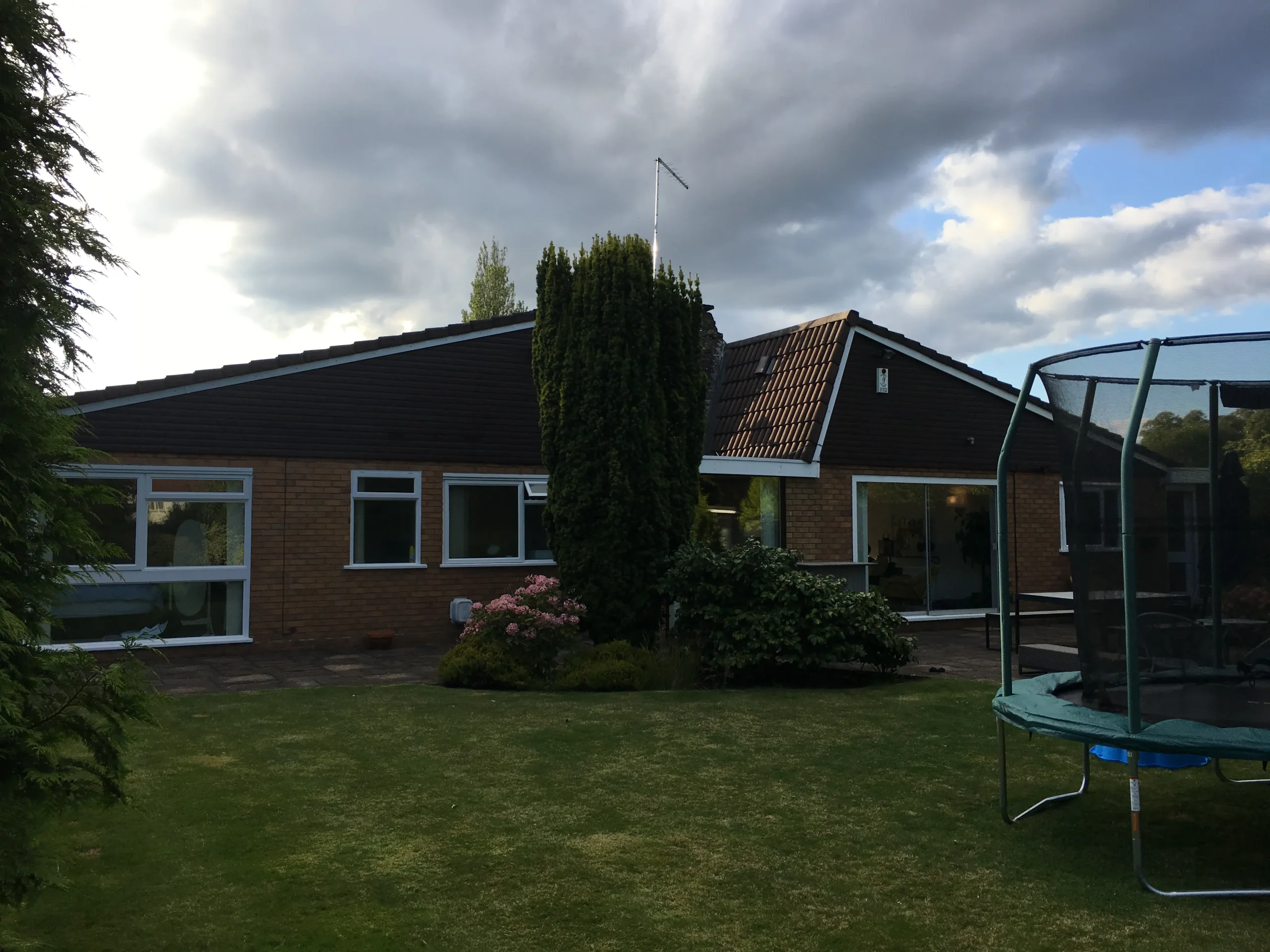 Existing rear elevation prior to extension and remodelling, with low horizontal rooflines, limited glazing and garden-facing rooms.
